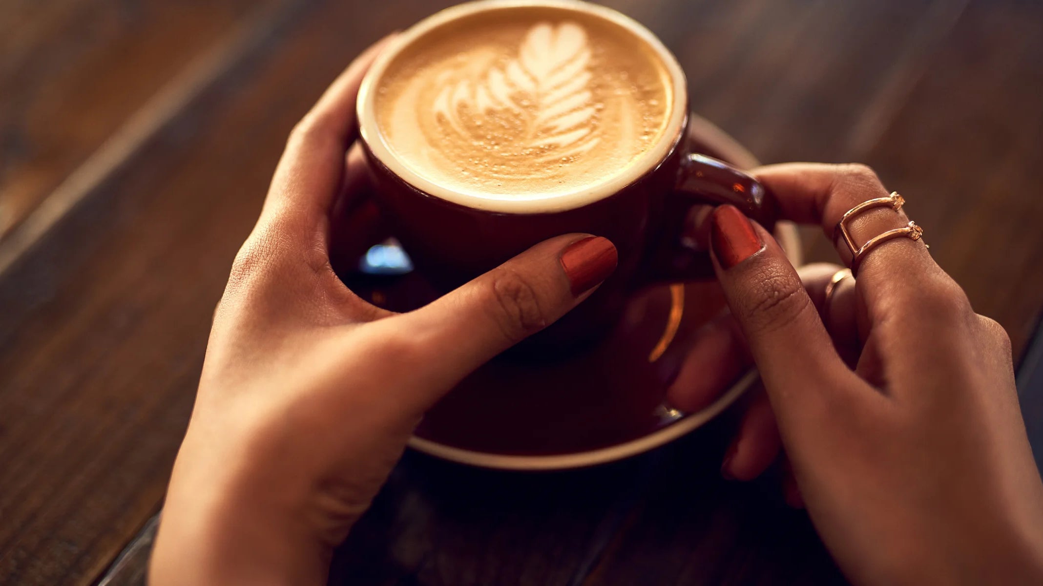 Une femme tenant une tasse de café sur une table en bois, illustrant l'achat de café.