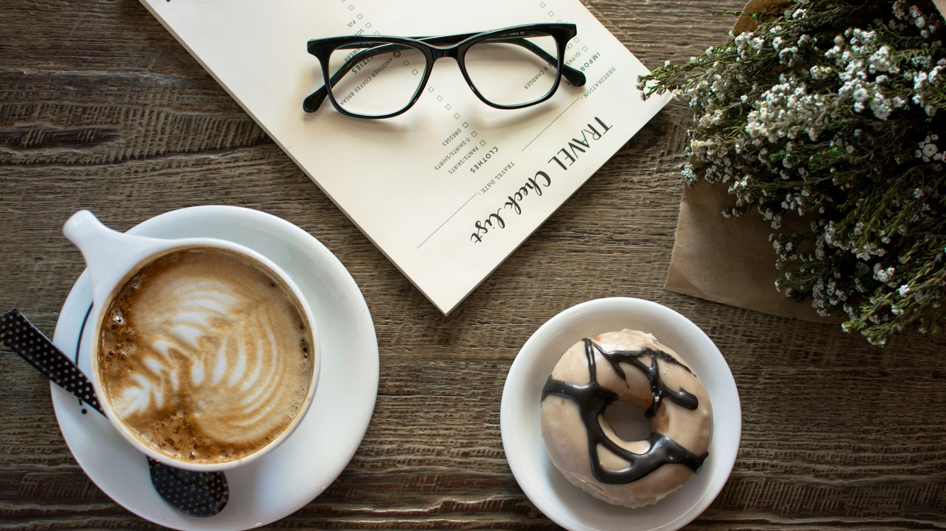 Cappucino sur une table avec un beigne et des lunettes