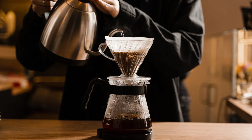 Une personne verse du café dans une cafetière à filtre.