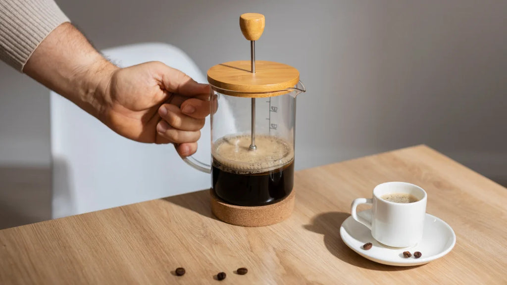 Une personne tenant une cafetière à piston sur une table, préparant un café décaféiné.