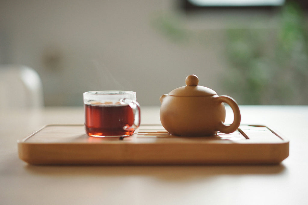 Café et feuilles de cascara sur une surface brune, créant une ambiance chaleureuse et naturelle.