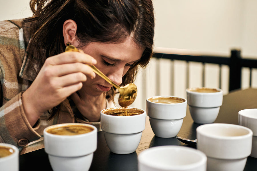 Une jeune femme sent une tasse de café lors d'un cupping