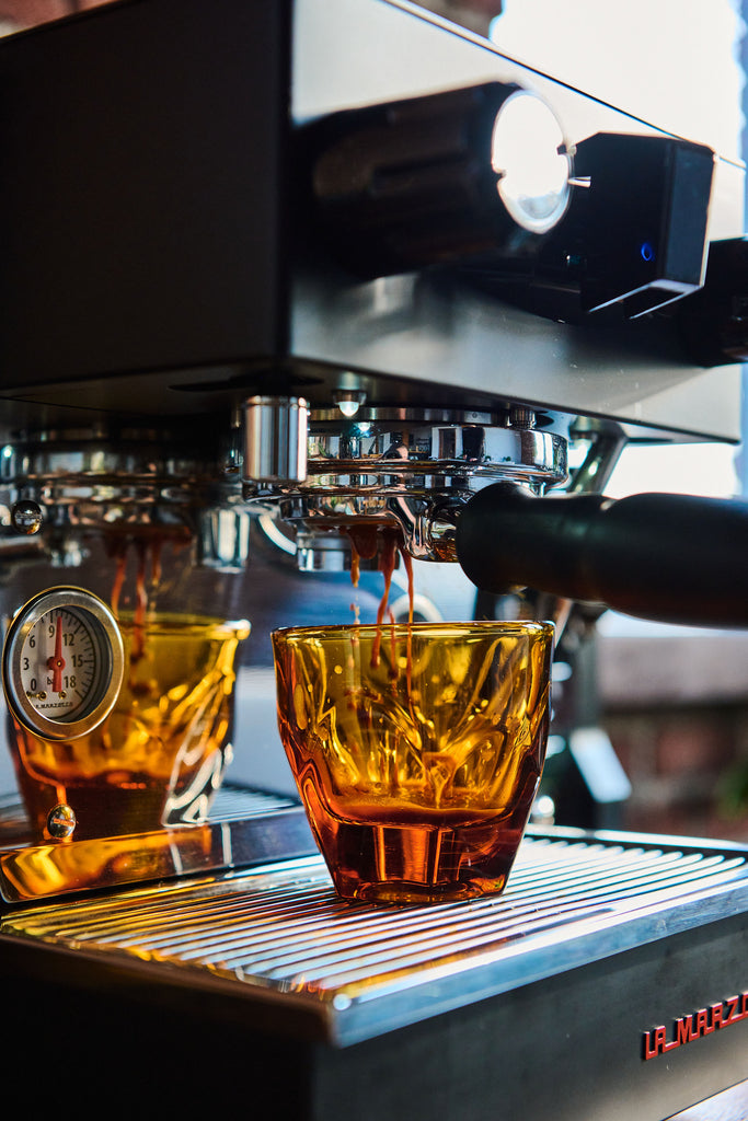 Tasse d'espresso jaune sous une La Marzocco