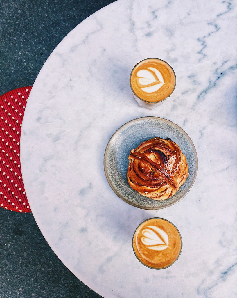 Deux cortados avec une patisserie sur une table en marbre